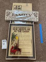Three pieces of wall art on carpet including framed sheet music print, wooden Family plaque, and small inspirational sign