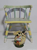 Front view of painted wooden child's chair with cast iron doorstop placed in front.
