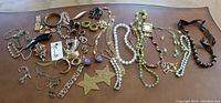 Wide view of all costume jewelry pieces including necklaces, rings, earrings, and brooches spread out on table.