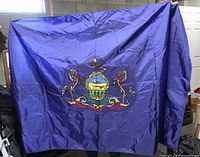 Full view of large dark blue flag with central Pennsylvania state coat of arms held up showing length and width