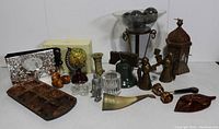 Overall view of mixed collectibles showing centerpiece, stone orbs, muffin pan, globe, lantern, candle holders and various metal decorative items.