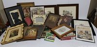 Photo showing assorted framed silhouette, antique photos, prints, and empty frames arranged overlapping on the floor.