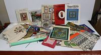 Full lot overview showing knitting needles, pattern booklets, buttons, embroidery cloths, and other sewing accessories.