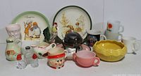 Wide view of various vintage collectible items including bowls, mugs, ceramic cookie jar, decorative plates, creamer, and salt and pepper shakers.