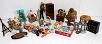 Photo showing entire lot with dolls seated in miniature chairs and bench, Shackman furniture figures and accessories, tea set box, wicker furniture, and silver-tone kitchenware.