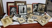 Overview of all framed and loose vintage photos and antique portraits arranged on a table showing frames of different colors and styles.