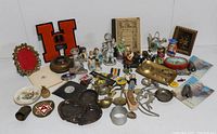 Photo of entire assortment showing porcelain figurines, a varsity letter patch 'H', various pins and patches, ashtray, small plates, and more assorted collectibles.