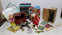 Overview of lot showing variety of vintage toys including tin bank toy, toy cars, children's books, and collectables.