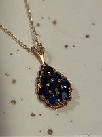 Close-up of pendant showing faceted blue sapphire cluster in gold setting