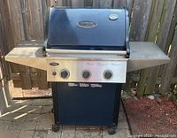 Front view of Vermont Castings BBQ grill showing the heavy cast lid, side shelves, control panel with three knobs and the steel base with casters.