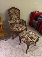 Photo of wood frame upholstered chair with high back and floral patterned fabric, positioned next to matching footstool with cabriole legs.