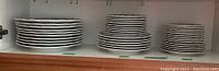 Stack of three groups of plates on shelf showing different sizes