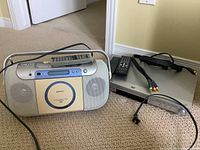 Sony portable CD recorder boombox and Panasonic DVD player with remotes and component cables on carpeted floor