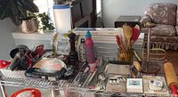 Wide view of the top shelf showing various kitchen tools and accessories including wooden spoons, pepper grinder, timers, and cooking utensils.