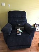 Front view of the blue La-Z-Boy power recliner chair showing the cushioned backrest, armrests, and remote placed on the seat.