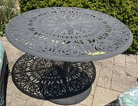Angled view of the patio table displaying detailed shadow pattern cast by the designed top and sturdy base.