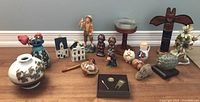 Full view of lot including Royal Doulton figurine, KLM miniature houses, pottery figurines and vases, brass parrot trinket box, and salt and pepper set.