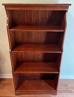 Full front view of the dark stained four-shelf wooden bookcase showing shelf sizes and overall condition.