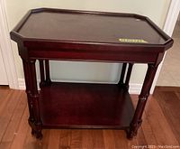 Front view showing the eight-legged dark stained wood table with lower shelf and visible ripple on surface.