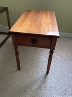 Full view of the wooden end table showing the top surface, legs, and drawer.