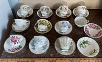Ten tea cups matched to their saucers with varied floral patterns and gold trim, three unmatched pieces