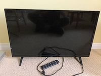 Photo of front view of LG 32-inch TV on carpet showing screen and legs.