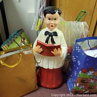 Front view of vintage Choir Boy outdoor light with some gift bags around it.
