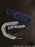 Photo of three necklaces and three bracelets laid flat on black surface