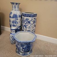 All four porcelain pieces together: large floor vase back left, rectangular umbrella stand back right, small bud vase front left, hexagonal planter with saucer front right.