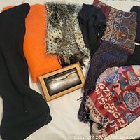 Displayed seven scarves in different colors and patterns with a boxed metallic silver leather wallet.