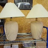 Pair of cream swirl vintage ceramic table lamps with shades on a shelf