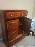 Front view of the tall boy armoire showing drawers and open cabinet door revealing shelving inside.