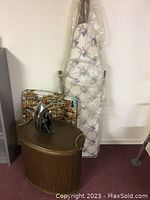 Vintage iron, ironing board, hamper and TV trays grouped together.