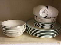 Stacked white bone china bowls, plates, and cups showing smooth round shapes and classic design.