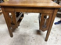 Front view of the writing desk showing the legs with carved side panels and the rectangular top surface.
