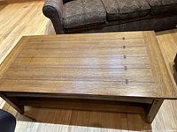 Top view of the wooden coffee table showing the wide planks with dark wood cross-ties and peg details.
