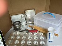 Photo showing assortment of baking tools including mini-muffin tin, rolling pin, flour sifter, cutter, cake carrier, canning jar, liquid measuring cup.