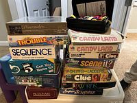 Stack of board games and puzzle boxes visible from front and side showing titles and packaging condition.