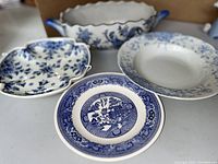 Three ceramic plates with blue and white floral and traditional designs displayed together