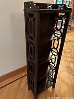 Slender four-tier bookcase showing lattice fretwork side panels, four fixed shelves and gallery top rail