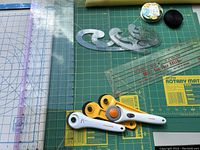Cutting mat surface with rotary cutters, curved rulers and clear straight rulers