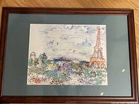Large framed Parisian landscape print by Raoul Dufy, showing watercolor image with Eiffel Tower and nature, brown wood frame with muted teal matting.
