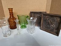 Two carved wooden plaques with raised floral design, glassware including green glass pitcher, cut glass vases, amber decanter