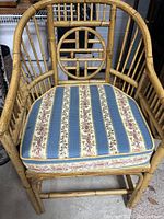 Front view of the bamboo and rattan armchair with the cushion placed on the seat, showing the full chair structure and fabric pattern.
