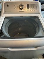 Top view of white GE top-loading washing machine with glass lid and interior drum
