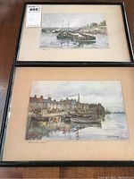 Pair of framed coastal-themed prints placed on table, one above the other showing details of scene and framing.
