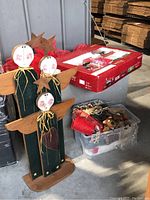 Three wooden angels with painted faces and feathered wings next to boxed Santa train model