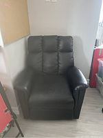 Front view of black leather-like electric recliner chair showing cushioned backrest, seat, and armrests.