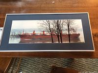 Full view of the framed photograph on a wooden surface showing the entire ship and frame.