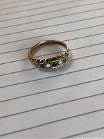 Front angle of the 10kt gold ring showing garnet and opal stones mounted in a row on the band.